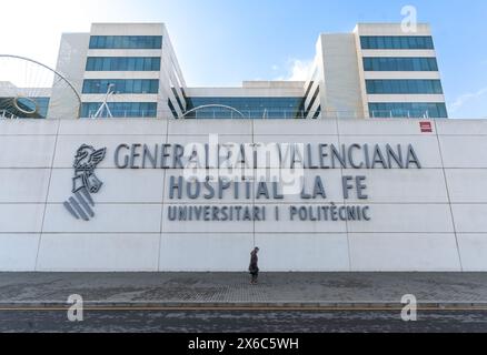 Une personne portant un masque passe devant le grand panneau du gouvernement valencien et l'hôpital universitaire public de la Fe à Valence. Banque D'Images