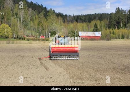 Travail dans les champs avec le tracteur Valtra et le semoir Junkkari Simulta 3000T un jour de printemps, vue arrière. Copier l'espace. Salo, Finlande. 12 mai 2024. Banque D'Images