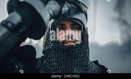 Chevalier médiéval sur le champ de bataille, regardant la caméra, son casque est ouvert. Portrait de puissant guerrier, Roi, soldat à la guerre, conquête, Croisade. Scène dramatique, reconstitution historique cinématographique Banque D'Images