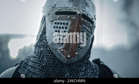 Portrait d'un chevalier médiéval sur le champ de bataille, casque fermé prêt pour la bataille. Portrait de puissant guerrier, Roi, soldat à la guerre, conquête, Croisade. Scène dramatique, reconstitution historique cinématographique Banque D'Images