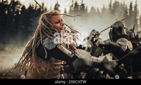 Epic Battlefield : puissant guerrier féminin attaquant, combattant avec épée, frappant l'ennemi avec des coups mortels. Âge sombre bataille médiévale des soldats chevaliers. Reconstitution historique cinématographique. Banque D'Images