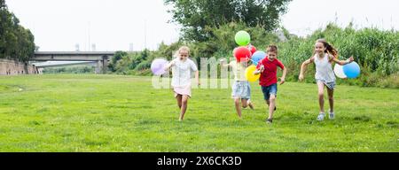 Les enfants avec des ballons courent dans le parc d'été Banque D'Images