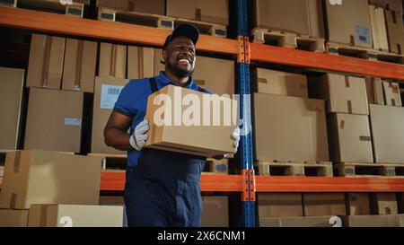 Beau travailleur noir homme sort de la boîte de carton de transport d'entrepôt et la charge dans le camion de livraison. Frontline Professional Hero livrant des commandes en ligne de commerce électronique. Banque D'Images