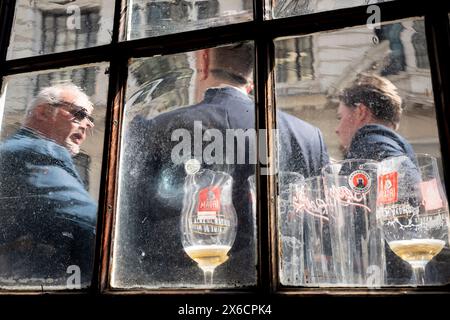 Trois hommes d'affaires et leurs verres de bière presque vides sont vus à travers le verre dépoli d'une fenêtre de pub, dans la City de Londres, le quartier financier de la capitale, le 9 mai 2024, à Londres, en Angleterre. Banque D'Images