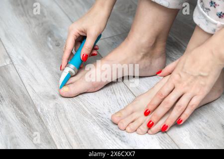 femme ponçant ses ongles d'orteils avec une ponceuse. mycose des ongles. maladie de l'ongle de pied. femme prenant soin des ongles des orteils. ongle jaune. meuleuse d'ongles électrique. problème Banque D'Images