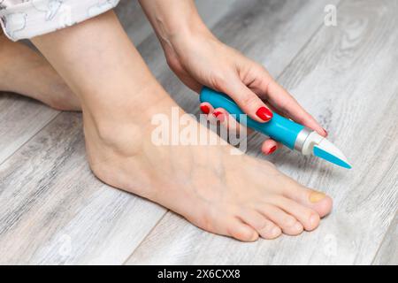 femme ponçant ses ongles d'orteils avec une ponceuse. mycose des ongles. maladie de l'ongle de pied. femme prenant soin des ongles des orteils. ongle jaune. meuleuse d'ongles électrique. Banque D'Images