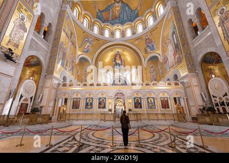 Une femme à l'intérieur de l'intérieur extrêmement orné et décoratif de l'église ou du temple St Sava. Une des plus grandes églises orthodoxes du monde. Avril 2024 Banque D'Images