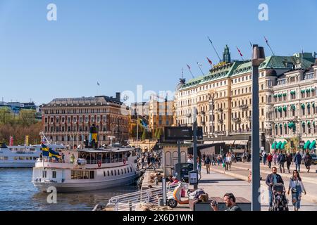 Le Grand Hôtel et les gens marchant le long des voies navigables près de Strömkajen, un endroit populaire pour les bateaux touristiques et les bateaux de banlieue. Printemps et soleil éclatant Banque D'Images