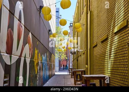 Ruelle vibrante avec tulipes murales et lanternes jaunes, scène de restauration urbaine Banque D'Images