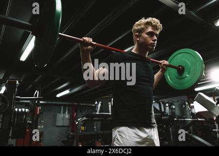 Prise de vue à angle bas d'un sportif faisant des squats à barre au gymnase CrossFit Banque D'Images