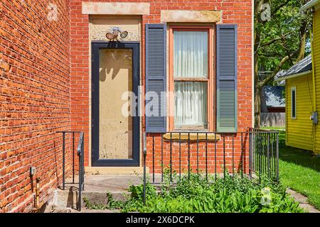 Maison en brique vintage avec porte jaune dans un cadre de banlieue, vue au niveau des yeux Banque D'Images