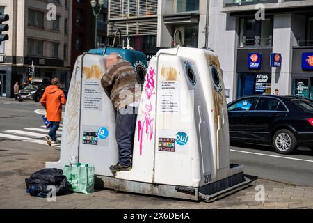 Homme ramassant et ramassant une bouteille consignée dans un bac de recyclage de verre pour la ramener à un magasin et avoir de l’argent | un homme tente de recu Banque D'Images