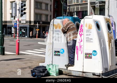 Homme ramassant et ramassant une bouteille consignée dans un bac de recyclage de verre pour la ramener à un magasin et avoir de l’argent | un homme tente de recu Banque D'Images