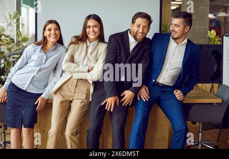 Groupe d'un heureux souriant gens d'affaires regardant la caméra, ayant du plaisir debout dans le bureau. Banque D'Images