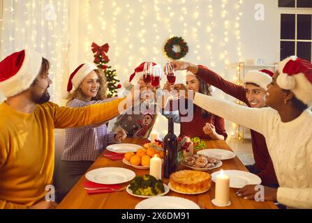 Groupe de jeunes amis multiraciaux joyeux célèbrent Noël dans une atmosphère chaleureuse à la maison. Banque D'Images
