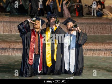 Austin Texas USA, 11 mai 2024 : les diplômés de la nouvelle université du Texas à Austin pataugeaient et éclaboussaient dans la fontaine de Littlefield immédiatement après leur cérémonie d'ouverture qui s'est tenue à proximité dans le stade de football de l'école. Le dunk festif est une tradition de longue date sur le campus. ©Bob Daemmrich Banque D'Images