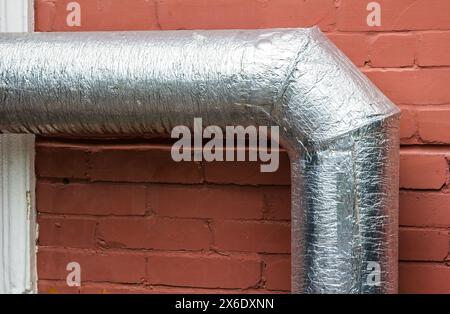 Tuyaux de ventilation en métal sur le mur extérieur d'un bâtiment industriel beige sur fond. Banque D'Images