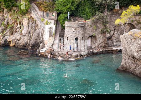 Les vacanciers appréciant l'eau transparente de Cannon Bay, une petite plage rocheuse accessible par des marches raides, Portofino, Gênes, Ligurie, Italie Banque D'Images