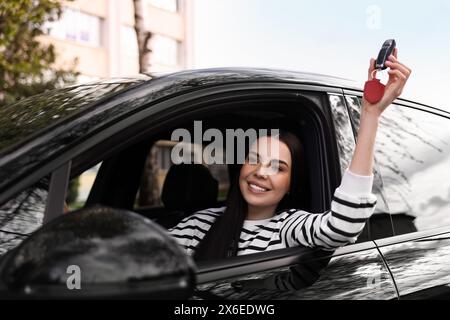 Femme tenant la clé à bascule de voiture à l'intérieur de son véhicule Banque D'Images