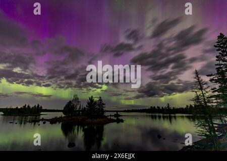 Les aurores boréales éclatent au-dessus d'un lac dans le Minnesota dans un ciel sombre au-dessus de l'arc-en-ciel brillant de lumière aurore Banque D'Images