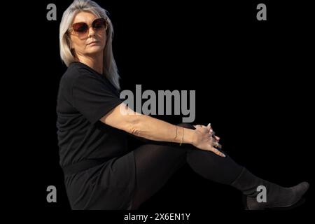 Ce portrait capture l’essence du charme sophistiqué d’une femme de 50 ans. Sa silhouette, définie par les lignes élégantes de sa tenue vestimentaire et le ch Banque D'Images