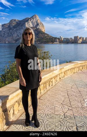 Ce portrait capture l’essence de la présence d’une belle femme dans la ville espagnole de Calpe, avec l’emblématique Mont Ifach qui s’élève majestueusement Banque D'Images