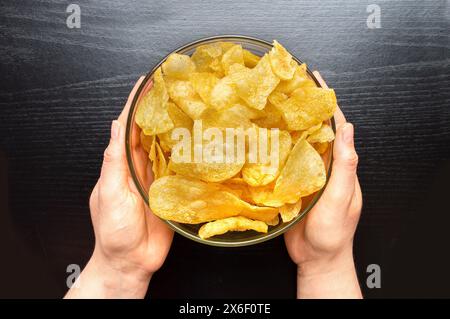 Vue de dessus prise de vue d'un bol de pommes de terre frites sur fond noir. Concept d'en-cas. Banque D'Images