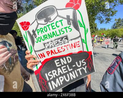 Palo Alto, Californie, États-Unis 12 mai 2024. Une manifestante pro-palestinienne à l'université de Stanford à l'occasion de la fête de l'indépendance d'Israël et de la fête des mères tente agressivement d'empêcher la caméra des photojournalistes de photographier les manifestants en la suivant avec une pancarte indiquant : « protéger la presse journaliste en Palestine : mettre fin à l'impunité Israël-États-Unis ». Des drapeaux palestiniens sont visibles en arrière-plan. (Crédit image : © Amy Katz/ZUMA Press Wire) USAGE ÉDITORIAL SEULEMENT! Non destiné à UN USAGE commercial ! Banque D'Images