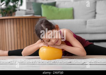 Petite fille avec balle faisant de la gymnastique à la maison Banque D'Images