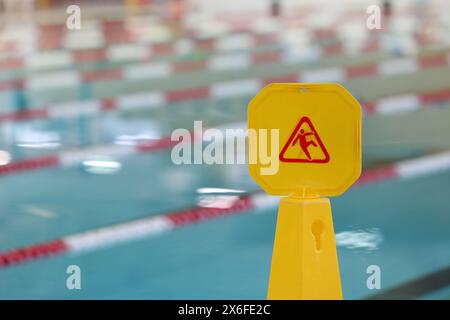 Panneau jaune de risque de chute de glissade dans une piscine publique. Responsabilité civile et assurance prévention des accidents et des blessures. Banque D'Images