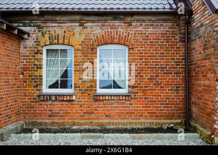 Le bâtiment en briques comporte deux fenêtres sur le côté, mettant en valeur la brique robuste. Il ressemble à un charmant cottage ou maison avec sa brique classique Banque D'Images