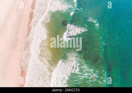 Un surfeur avec un tableau rouge sur le rivage d'une plage. Vue aérienne aérienne avec drone Banque D'Images