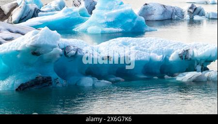 Un gros morceau de glace flotte dans l'océan. La glace est entourée d'eau et est partiellement submergée. La scène est calme et sereine, avec le bleu Banque D'Images