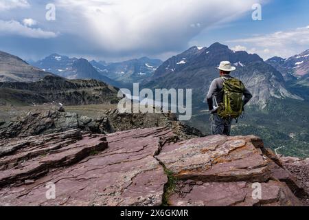 Un randonneur debout sur un point élevé dans la nature sauvage regardant vers le bas une vallée avec un lac, Two Medicine Lake de Scenic point, Glacier National Park Banque D'Images