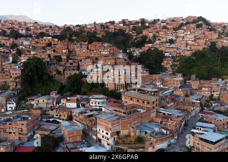 Vue aérienne de Caracas au coucher du soleil avec le quartier Petare, le plus grand bidonville du Venezuela et d'amérique latine, avec la montagne Avila dans l'arrière-pays Banque D'Images