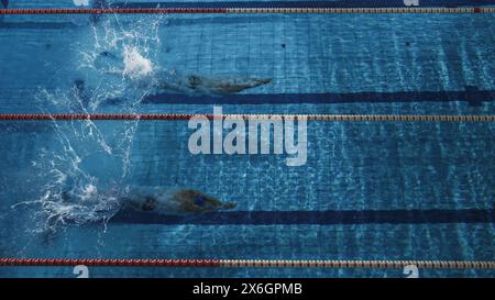 Course de natation : deux nageurs professionnels sautent plonger dans la piscine, des victoires plus fortes et plus rapides. Les athlètes concourent les meilleures victoires Championnat, record du monde. Vue aérienne de haut en bas Banque D'Images