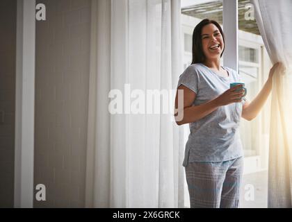 Femme, café et rideau ouvert le matin, porte vitrée et réveil frais avec le lever du soleil à l'hôtel prêt pour la journée. Routine, vue extérieure et vacances ou Banque D'Images