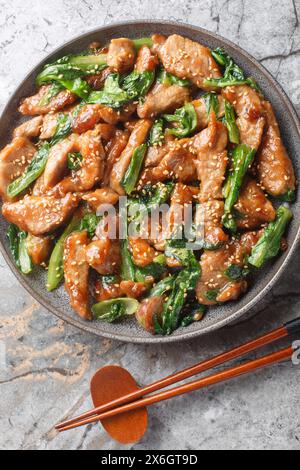 Filet de porc et Stir-Fry romaine avec sauce soja, graines de sésame en gros plan sur l'assiette sur la table. Vue de dessus verticale Banque D'Images