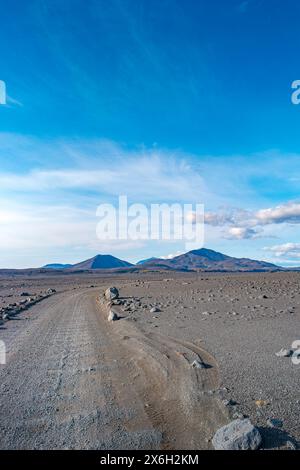 Couverture avec chemin de terre près du volcan Herdubreid dans le désert lunaire volcanique sans vie dans les Highlands, avec des pierres et des rochers jetés par l'éruption volcanique Banque D'Images