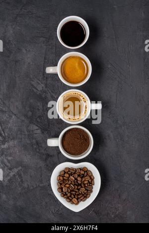 Vue de dessus. Certains types de café dans différentes tasses disposées en rangée verticale sur un fond noir Banque D'Images