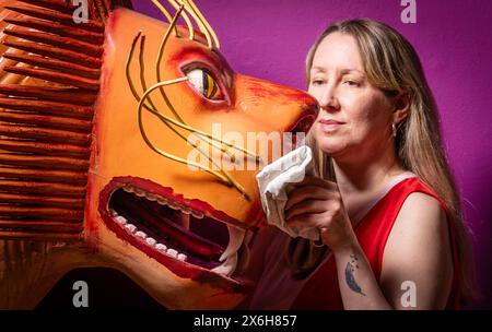 Kat Baxter conservateur de l'archéologie, nettoie un cercueil en forme de lion qui a été fabriqué par le charpentier de cercueil ghanéen mondialement célèbre Paa Joe, connu pour sculpter des abebuu adekai personnalisés élaborés, ou «boîtes de proverbe», qui visent à capturer des éléments de la vie de la personne décédée. Le cercueil fait partie de l'exposition Living with Death au Leeds City Museum, qui explore les différentes façons dont les gens vivent la mort, la mort et le chagrin. Date de la photo : mercredi 15 mai 2024. Banque D'Images