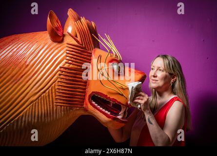 Kat Baxter conservateur de l'archéologie, nettoie un cercueil en forme de lion qui a été fabriqué par le charpentier de cercueil ghanéen mondialement célèbre Paa Joe, connu pour sculpter des abebuu adekai personnalisés élaborés, ou «boîtes de proverbe», qui visent à capturer des éléments de la vie de la personne décédée. Le cercueil fait partie de l'exposition Living with Death au Leeds City Museum, qui explore les différentes façons dont les gens vivent la mort, la mort et le chagrin. Date de la photo : mercredi 15 mai 2024. Banque D'Images