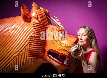 Kat Baxter conservateur de l'archéologie, nettoie un cercueil en forme de lion qui a été fabriqué par le charpentier de cercueil ghanéen mondialement célèbre Paa Joe, connu pour sculpter des abebuu adekai personnalisés élaborés, ou «boîtes de proverbe», qui visent à capturer des éléments de la vie de la personne décédée. Le cercueil fait partie de l'exposition Living with Death au Leeds City Museum, qui explore les différentes façons dont les gens vivent la mort, la mort et le chagrin. Date de la photo : mercredi 15 mai 2024. Banque D'Images