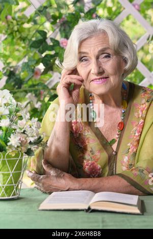 Belle femme âgée lit un livre à la maison de campagne Banque D'Images