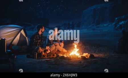 Heureux couple nature Camping dans le Canyon, assis près d'un feu de camp, boire du café, regarder Night Sky. Deux jeunes voyageant parlent, regardez les étoiles de la voie lactée. En voyage de vacances inspirant Banque D'Images