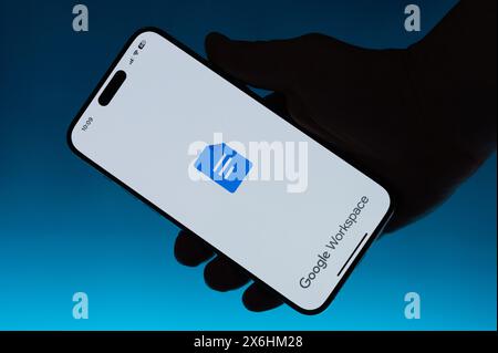 New York, États-Unis - 6 mai 2024 : utilisation de l'application Google Workspace sur smartphone dans la main isolé fond bleu dégradé Banque D'Images