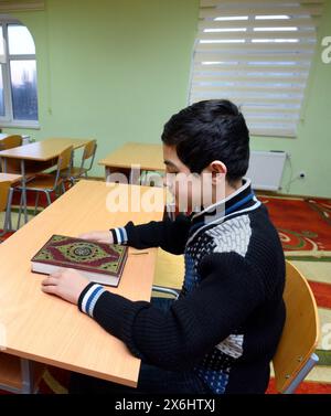Salle de classe de la medrese. Garçon musulman assis à un bureau d'école, Quran placé devant lui. 21 octobre 2018. Centre culturel islamique, Kiev, Ukraine Banque D'Images