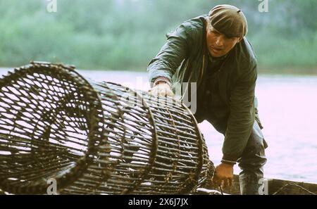 République socialiste de Roumanie dans les années 1970 Pêcheur sur un bateau en bois attrapant des poissons avec un grand piège en entonnoir. Banque D'Images