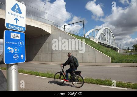 Cycliste utilisant une piste cyclable passant sous un pont de chemin de fer sur le canal Albert près de Hasselt, Belgique. Banque D'Images