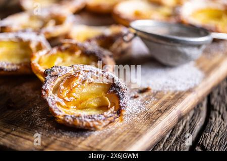 Mini tartes faites de pâte feuilletée et de pommes tranchées saupoudrées de sucre en poudre Banque D'Images